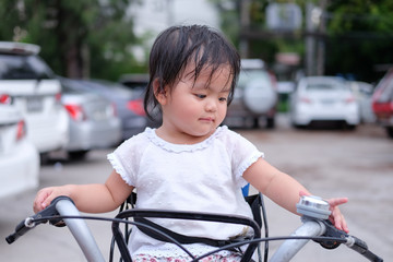 Obraz premium Cute Baby girl is sitting on a bicycle., close-up portrait, Portrait of Asian beautiful baby girl of 1 year and 3 months old.