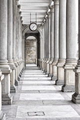Colonnade of tall columns with clock by the ceiling
