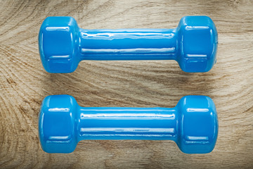 Blue dumbbell weights on wooden board sports training concept