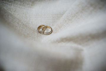 Wedding rings on fabric light brown background