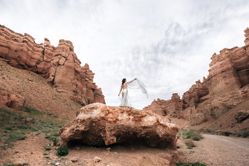 Young bride in wedding dress in mountain canyon
