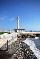 View of the whitewashed lighthouse along the rugged coastline, Torrox Costa, Spain.