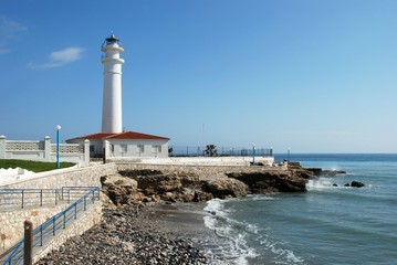View of the whitewashed lighthouse along the rugged coastline, Torrox Costa, Spain. © arenaphotouk