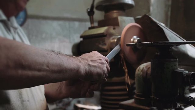 Craftsman sharpening knife in the workshop