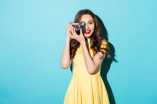 Pretty girl in dress taking photo on a retro camera