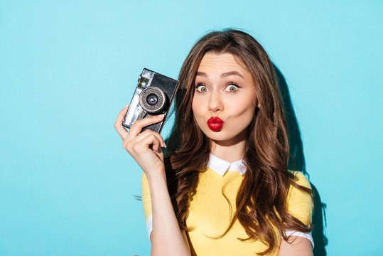 Portrait of a funny girl in dress holding vintage camera