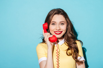 Smiling pretty woman in dress holding retro telephone tube