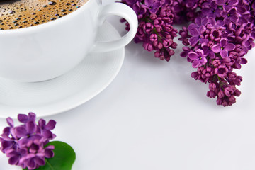 Cup of coffee with violet lilac flowers