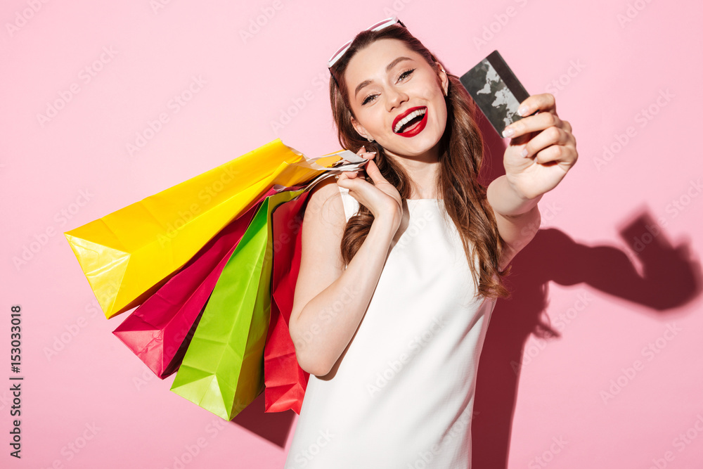 Canvas Prints Happy young brunette woman holding credit card and shopping bags