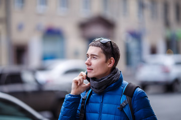 Young man talking on phone, standing on street