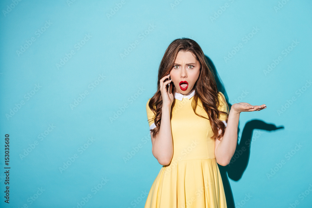 Poster upset surprised girl in dress talking on mobile phone