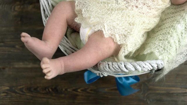 Legs of small child. White basket with baby.