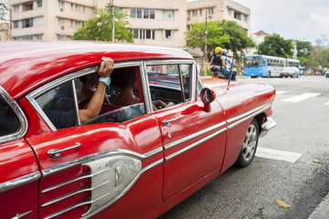 Vintage American car serving as shared taxi driving along a street in Central Havana, Cuba
