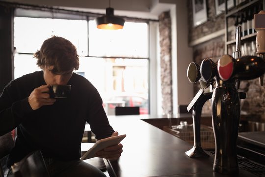 Man using digital tablet while having coffee
