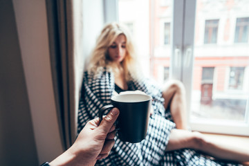 girl sitting on a window in a blanket