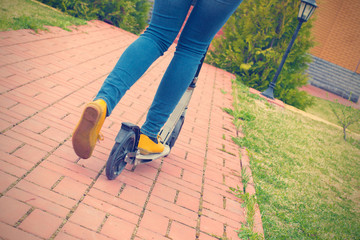 Legs in jeans and sneakers on a kick scooter