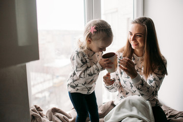 Mom and daughter drink something with mug