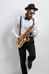 Naklejka premium Jazz musician leaning against a wall and playing saxophone