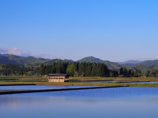 小屋のある風景　春の田植え前の田んぼ　青空