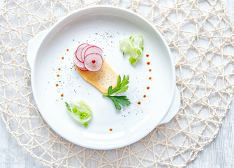 Diet chips of turnip and radish with cucumber, green onion and spices on a white round plate, top view. The horizontal frame.