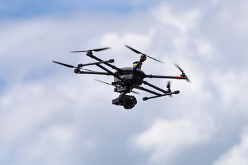 UAV drone copter high up in the blue sky surrounded by clouds