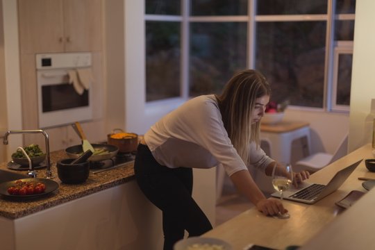 Beautiful woman using laptop in kitchen