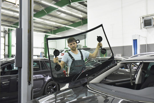 Car mechanic in a workshop changing car window