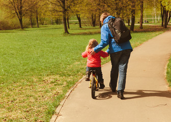 Fototapeta premium father teaching little daughter to ride bicycle
