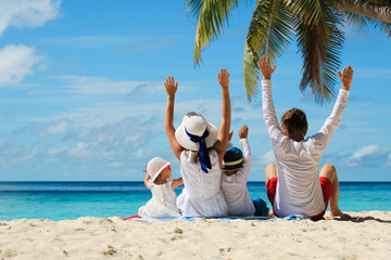 happy family with two kids hands up on beach