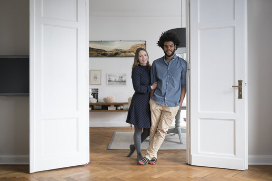 Smiling couple at home standing in door frame