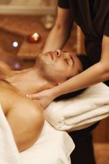 Handsome young man enjoying massage at spa center
