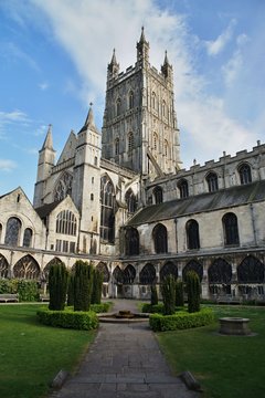 Gloucester Cathedrale in Enhland. Green garden, tower and blue sky.