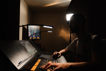 A lighting engineer works with lights technicians control on the concert show. Professional light mixer, mixing console. Equipment for concerts.