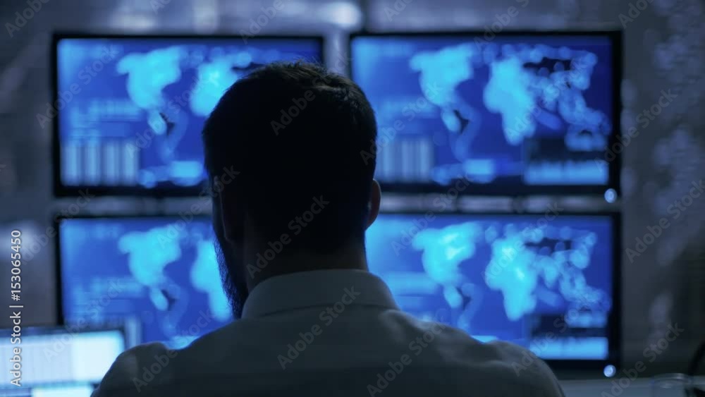 Poster late at night security operator attentively observes his monitors with location sensitive informatio