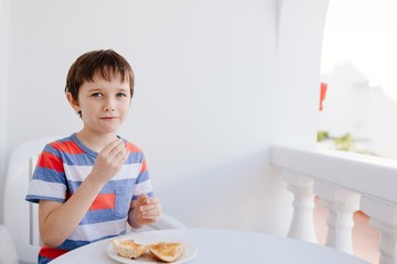 Child eats a bread roll with jam for breakfast