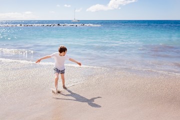 Happy child boy playing on beach
