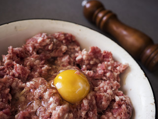 Minced meat for cutlets with raw egg in an enamel bowl.