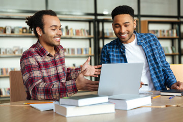 Two multicultural male students studying with laptop