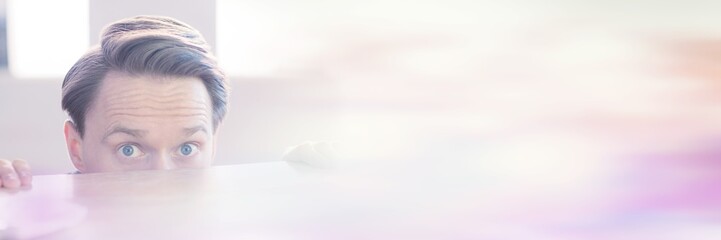 Nervous businessman peeking over desk