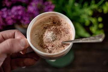 White cup with foam capuccino in hands
