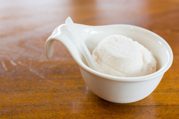 White ice cream in cup on wooden table