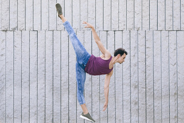 modern male dancer in motion performing a ballet pose with jeans