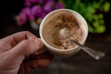 White cup with capuccino in hands 