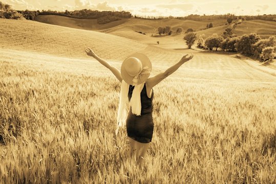 Woman with red dress posing for photographs in wheat field in the Tuscan hills