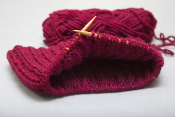 The process of knitting a scarf-snud on circular wooden knitting needles from red wool, warm winter asseksuar
