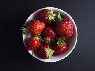 Fresh, red, ripe strawberries in white bowl isolated on black background