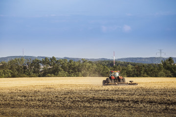 Fototapeta na wymiar Tractor driving in field, autumn rural landscape. Agriculture