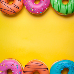 A set of sweet donuts on orange background. Top view with copy space