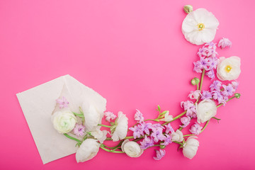 Flowers and paper envelope on pink background. Flat lay, top view. Floral round frame