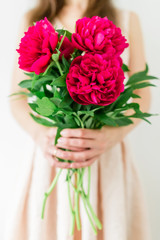 Happy young woman holding red peony bouquet in hands. Sweet romantic moment